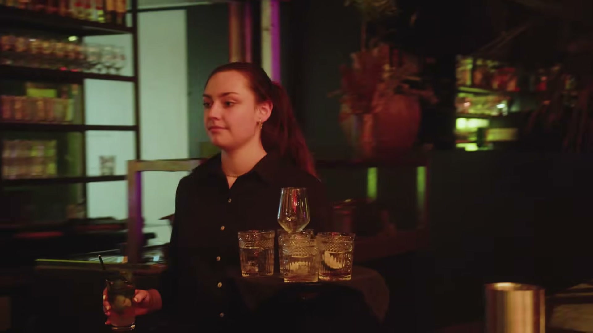 Iemand van de bediening brengt glazen naar tafel in de avond