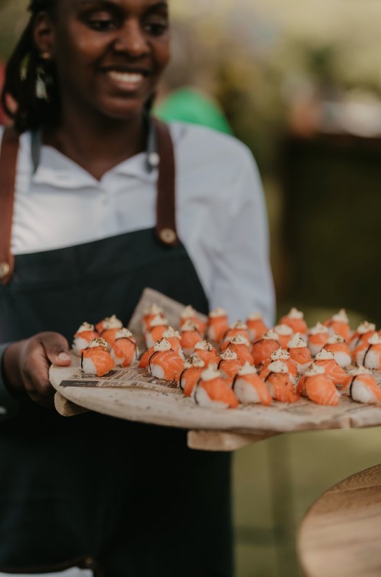 Een plank met hapjes van zalm, rondgedragen door iemand van de catering